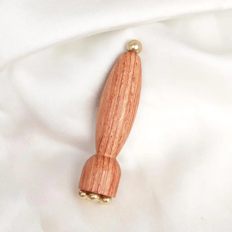 Augen-Massagestab aus Messing und Holz auf weichem Samthintergrund