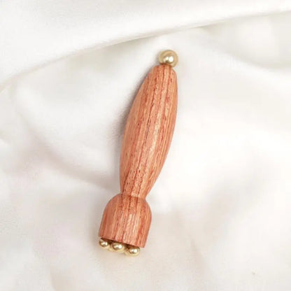 Augen-Massagestab aus Messing und Holz auf weichem Samthintergrund